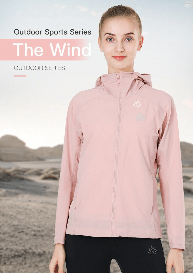 Woman wearing a pink waterproof sports jacket with hood, perfect for running and outdoor activities.